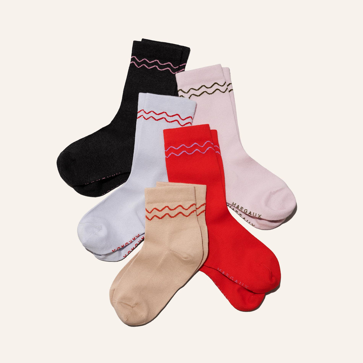 Five pairs of The Crew Sock - Poppy by Margaux, in black, light pink, light blue, red, and beige with wavy stripes near the cuff, are arranged overlapping—a perfect gift or addition to any Margaux gift box set.